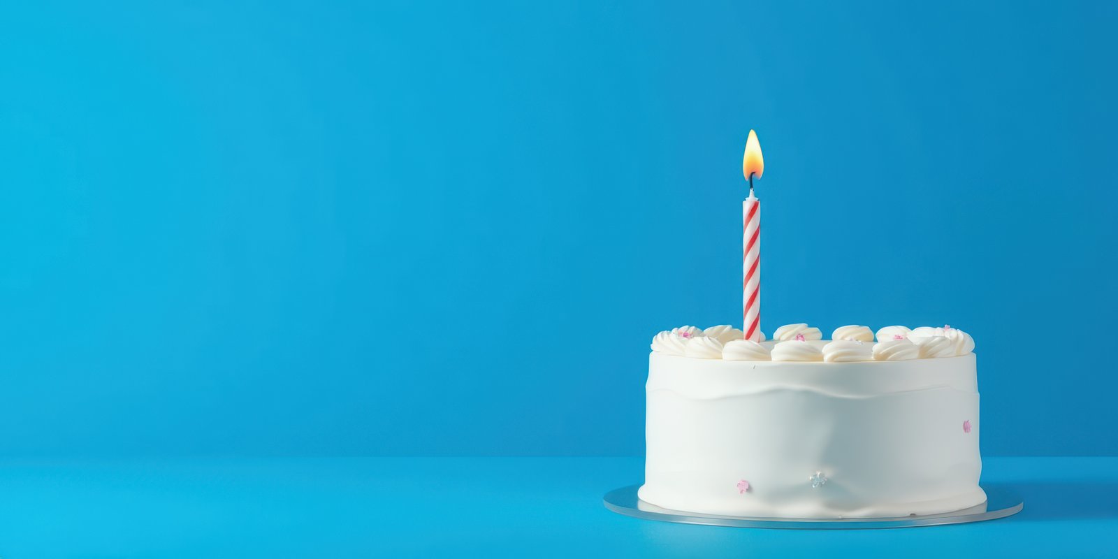 Delicious white birthday cake with candle on bright blue background
